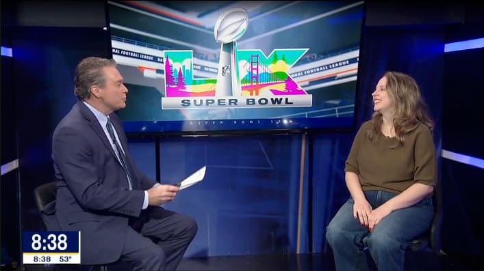 A FOX 4 News anchor interviewing a guest in the studio in front of a Super Bowl LX graphic