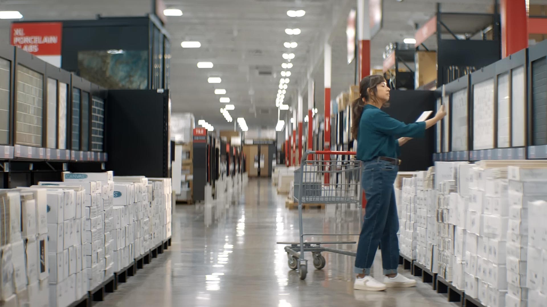 A shopper pushing a cart and browsing tile samples in a Floor & Decor store aisle