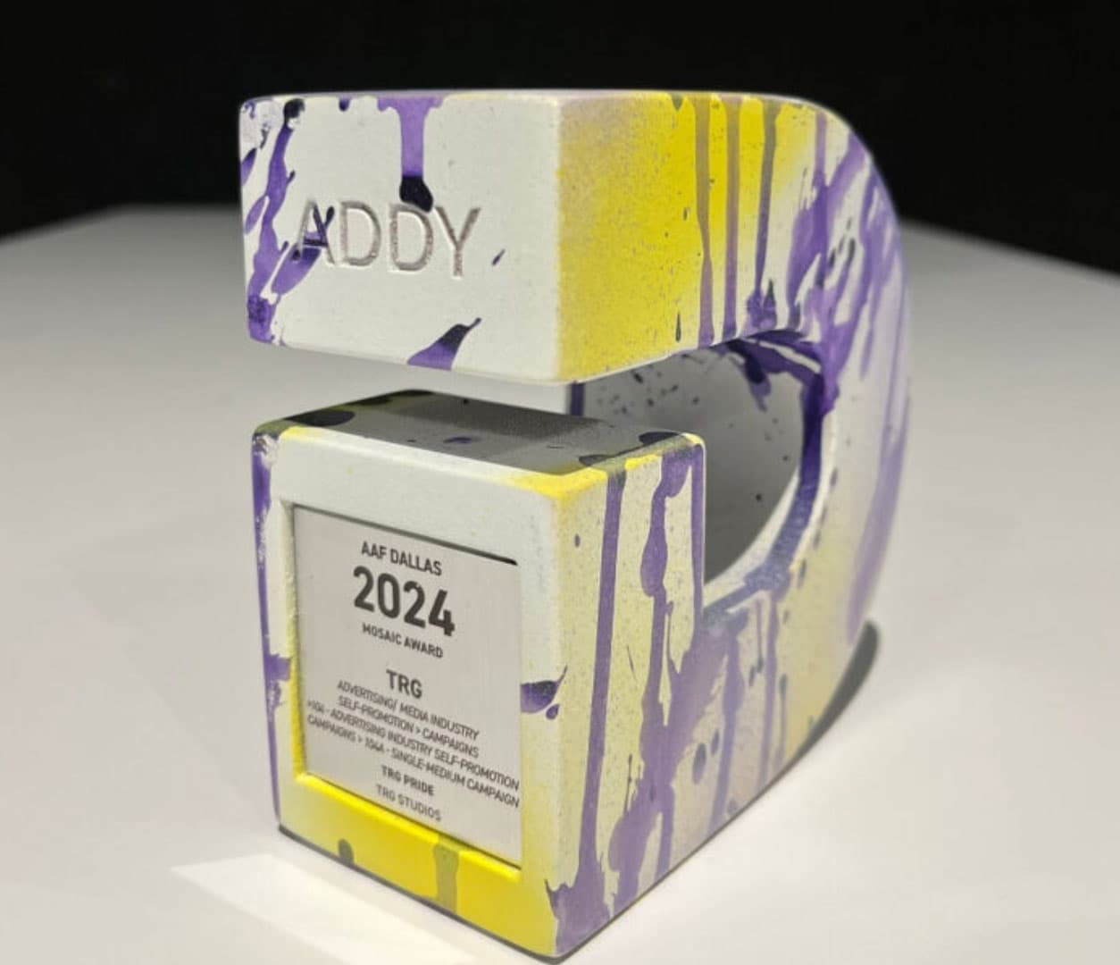 A close-up of TRG’s paint-splattered AAF Dallas 2024 Mosaic Award ADDY trophy